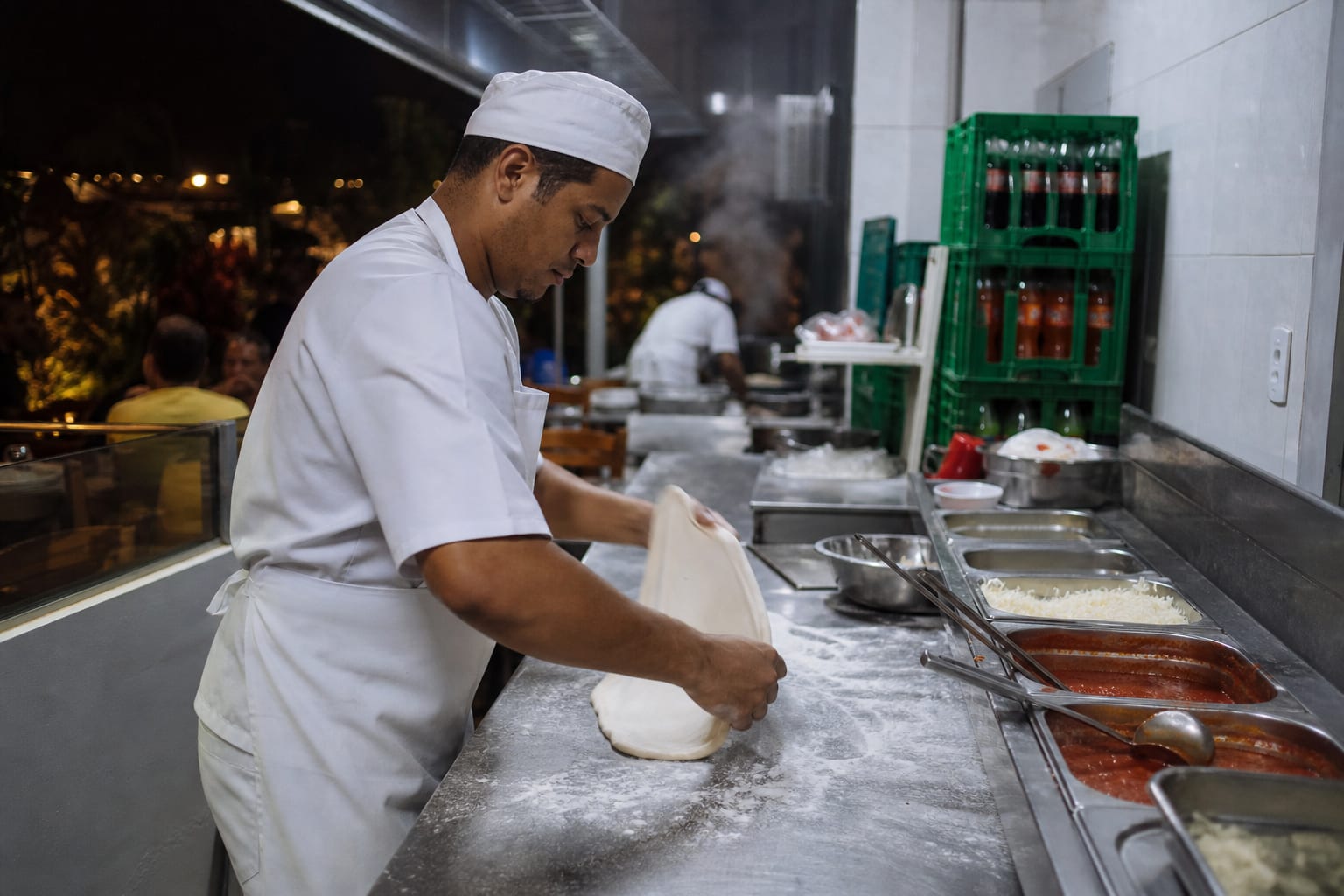 Pizzaiolo colocando pizza no forno a lenha com o salão cheio ao fundo
